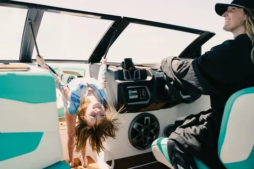 lady driving a boat with a girl playing nearby