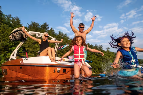 kids and parent jumping into water from boat